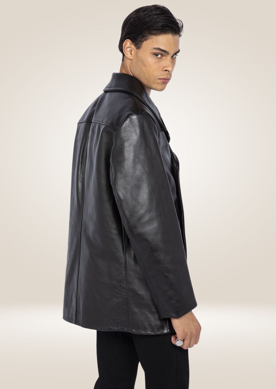 Man wearing a black cowhide leather pea coat in an outdoor urban setting, exuding rugged elegance and style