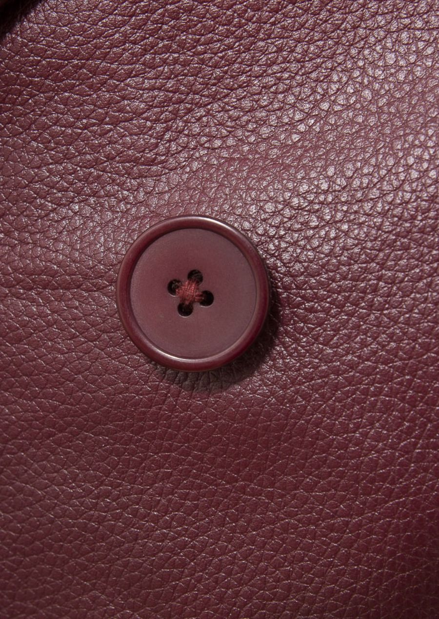 Close-up of the double-breasted buttons on the men's burgundy pea coat, highlighting the bold design details.