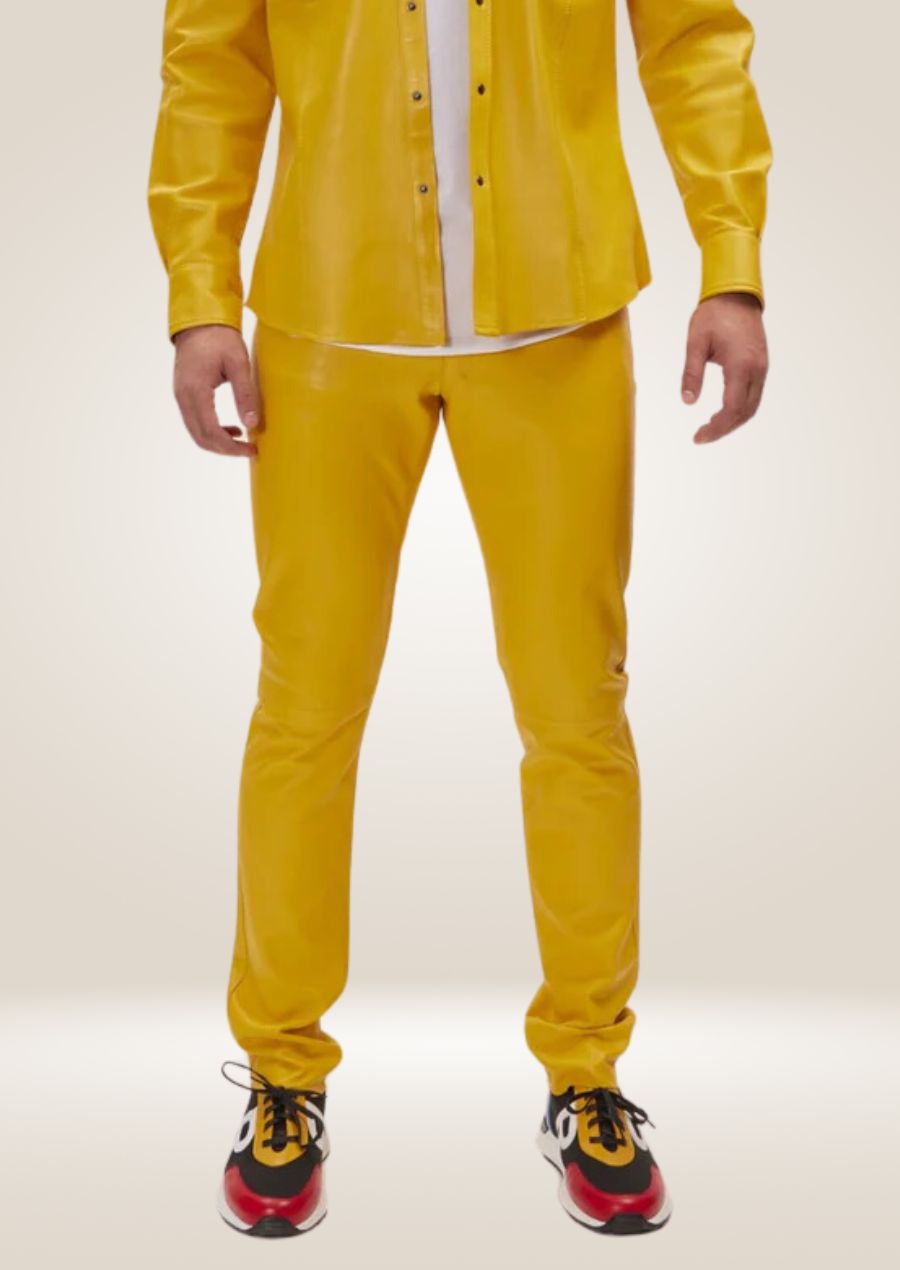 Men’s bright yellow leather pants with slim fit and front button closure, paired with multi-color sneakers.