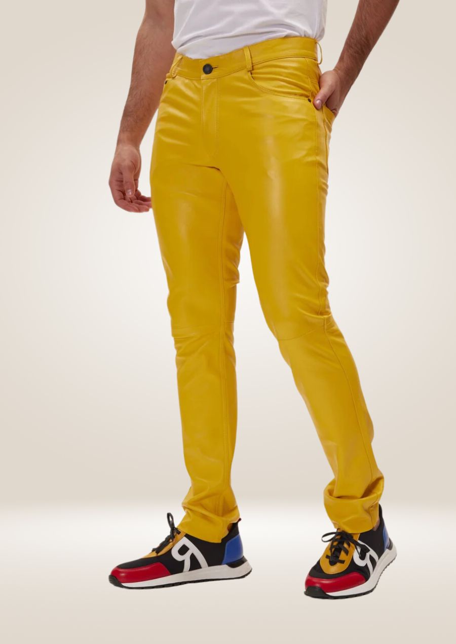 Men’s bright yellow leather pants with slim fit and front button closure, paired with multi-color sneakers.