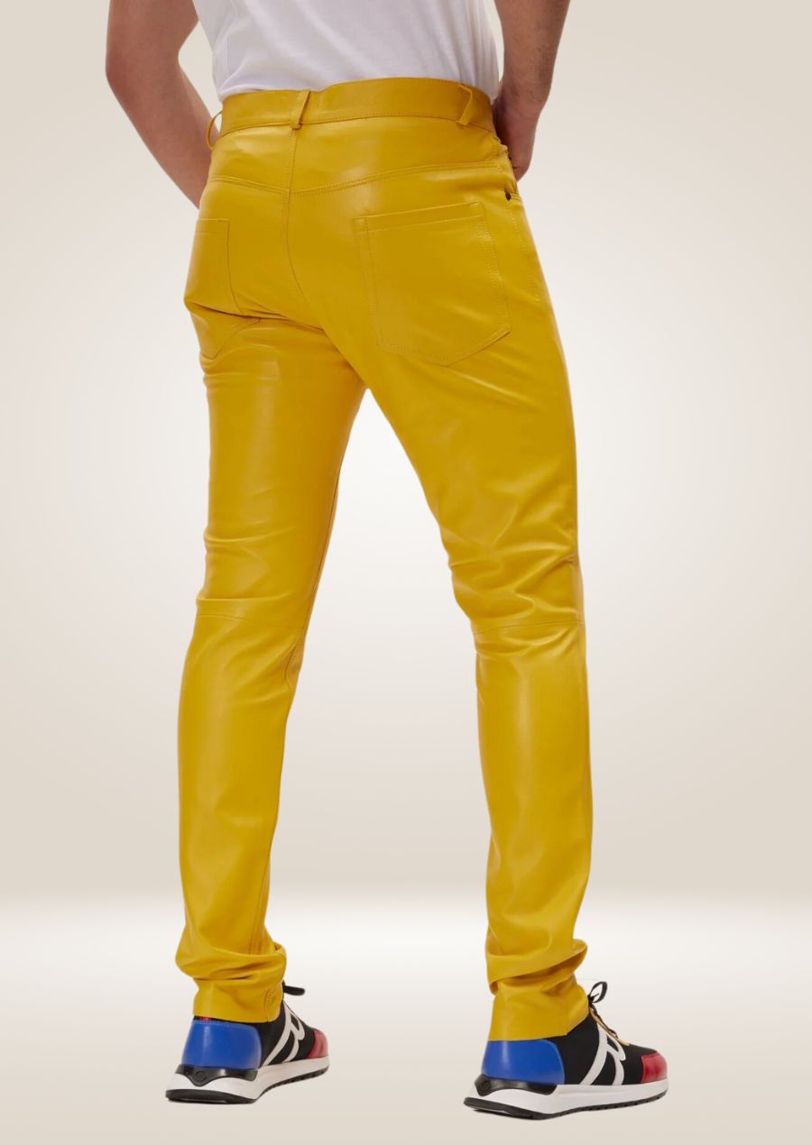 Men’s vibrant yellow leather pants paired with statement sneakers, showcasing modern fashion style.